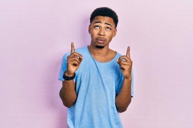 Gündelik mavi tişört giyen genç Afro-Amerikan adam üzgün ve üzgün görünüyor, parmaklarıyla yönü gösteriyor, mutsuz ve depresif.. 