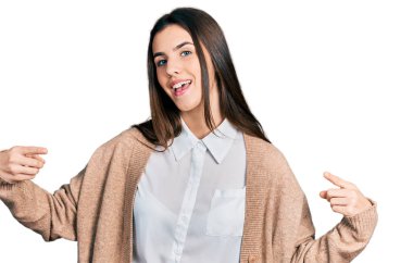 Genç esmer, sıradan beyaz gömlek ve ceket giyen, kendine güvenen, yüzünde gülümseme olan, kendini gururlu ve mutlu parmaklarıyla gösteren bir genç.. 