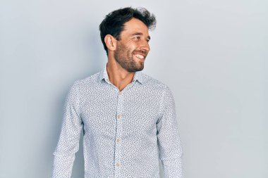 Sakallı, sıradan, şık gömlekli, yüzünde gülümseme, doğal bir ifade olan yakışıklı bir adam. Kendinden emin gülen. 