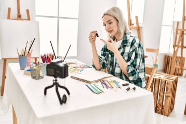 Genç ressam kız mutlu resim çiziyor. Sanat atölyesindeki masa başı resim dersinde otururken..