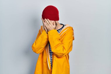 Sakallı, sarı yağmurluk giyen, suratını elleriyle kapatıp ağlayan beyaz bir adam. depresyon kavramı. 