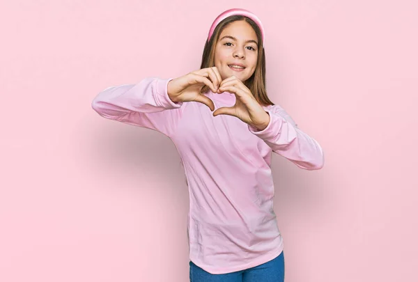 美しいブルネットの女の子は手でハートシンボルの形をして愛に笑みを浮かべてカジュアルなタートルネックセーターを身に着けています ロマンチックなコンセプト — ストック写真