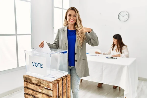 Mujer Rubia Joven Votando Poniendo Sobre Las Urnas Señalando Dedo —  Fotos de Stock