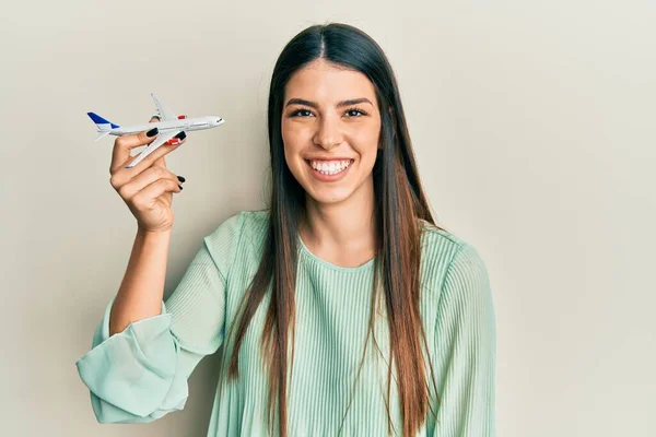 若いですヒスパニック女性保持飛行機おもちゃ見て正と幸せな立ちと笑顔で自信を持って笑顔示す歯 — ストック写真