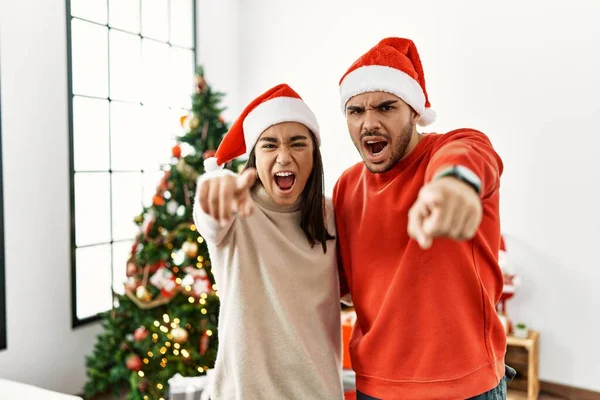 Jovem Casal Hispânico Junto Árvore Natal Apontando Descontente Frustrado Para — Fotografia de Stock