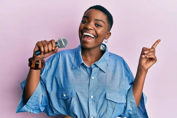 Joven Mujer Afroamericana Cantando Canción Usando Micrófono Sonriendo Feliz Señalando —  Fotos de Stock