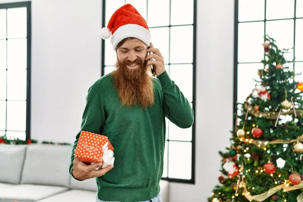 남자가 선물을 스마트폰으로 집에서 크리스마스 옆에서 이야기하고 있습니다 — 스톡 사진