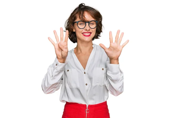 自信を持って幸せな笑顔ながらビジネススタイルとメガネを身に着けている若いヒスパニック系の女性が現れ 指番号9で指摘します — ストック写真