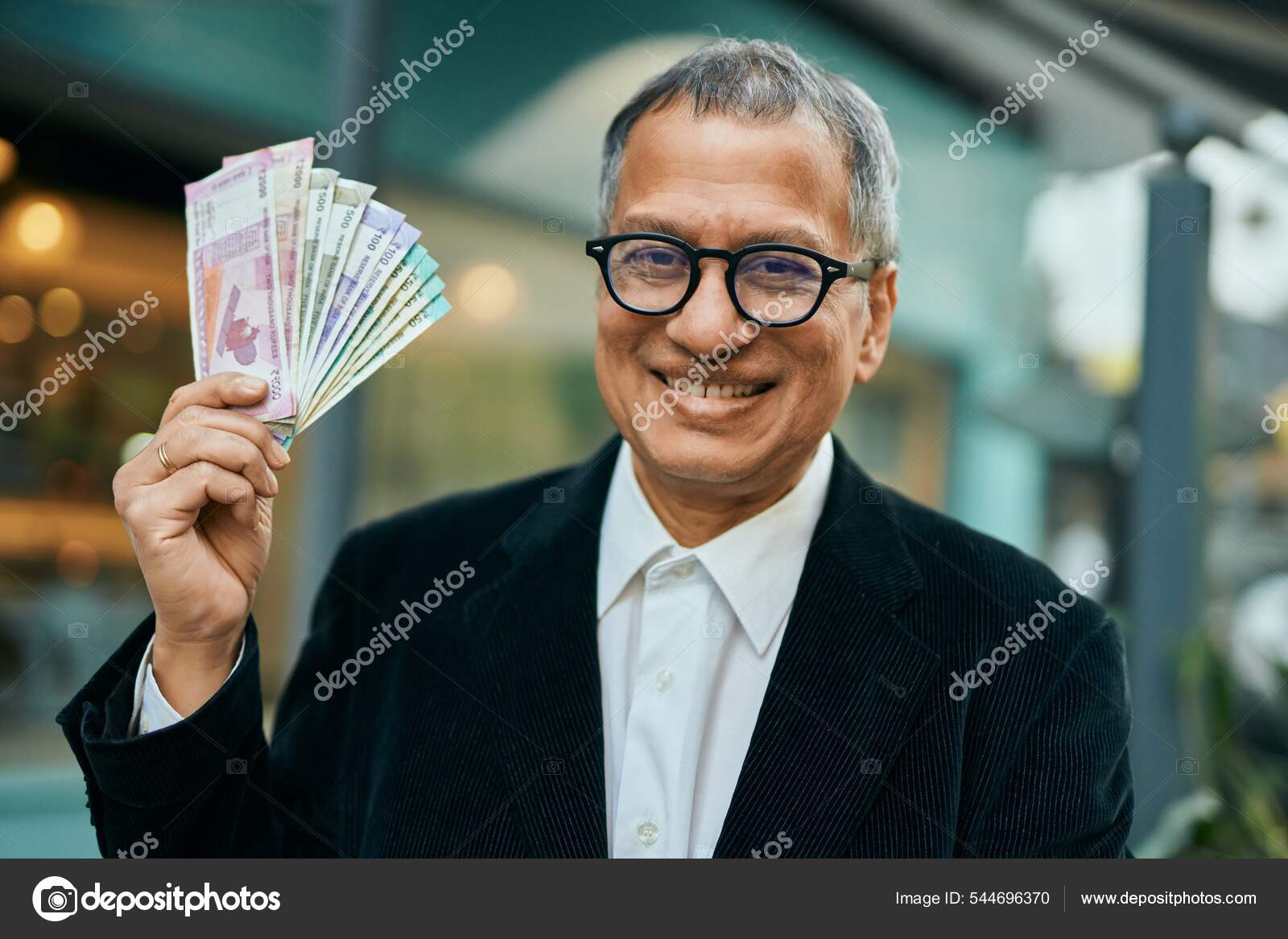 中年时代的东南亚人在城里拿着印度卢比钞票——图库图片© Krakenimages.com #544696370