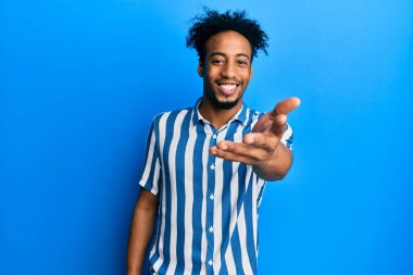 Sakallı, sıradan çizgili tişörtlü, genç Afro-Amerikan bir adam dostça gülümseyerek selamlama ve hoş geldin diyor. başarılı iş. 