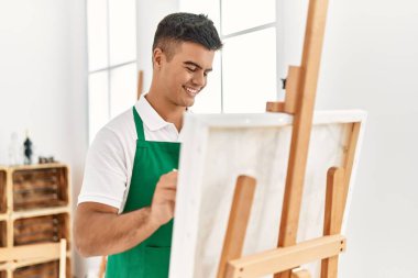 Genç İspanyol adam resim stüdyosunda kendine güvenen gülümsüyor.