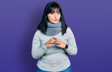 Kış eşarbı takan genç Latin kökenli kadın ve gülümseyerek gevşemiş ve neşeli parmaklar çapraz. Başarı ve iyimserlik 