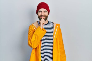 Sakallı, sarı yağmurluk giyen beyaz bir adam kameraya kollarını kavuşturup gülümseyen ve çenesini kaldıran bir adam. Olumlu düşünmek. 