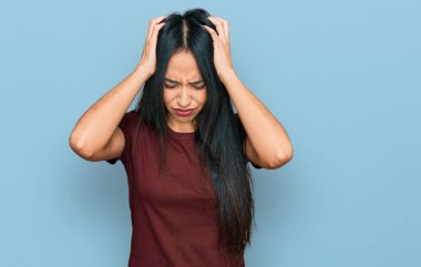 Genç İspanyol kız gündelik tişört giyiyor. Baş ağrısı çekiyor. Acı ve migren yüzünden çaresiz ve stresli. Eller başının üstünde.. 