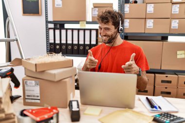 Depoda çalışan Latin kökenli genç bir çağrı merkezi ajanı mutlu ve komik yüzüyle kamerayı işaret ediyor. iyi enerji ve titreşimler. 