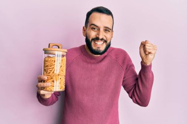 Sakallı genç adam elinde makarna kavanozuyla gururla bağırıyor zaferi ve başarıyı kutluyor. 
