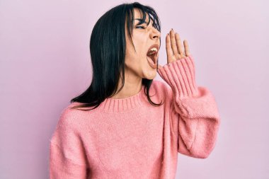 Kâküllü, kışlık süveter giyen genç esmer kadın el ve ağızla bağırarak ve yüksek sesle bağırıyor. iletişim konsepti. 