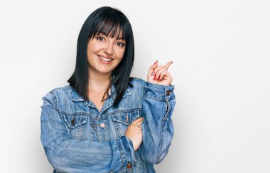 Yüzünde kocaman bir gülümseme olan, gündelik kıyafetler giyen genç İspanyol kadın, kameraya el ve parmak ile bakıyor.. 