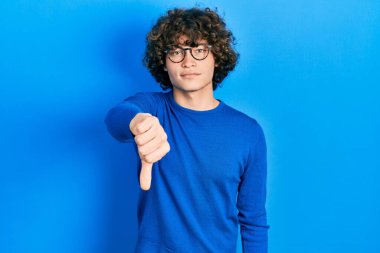 Yakışıklı, sıradan kıyafetler giyen, gözlüklü, mutsuz görünen, reddedilmiş ve olumsuz davranan genç bir adam. kötü ifade. 