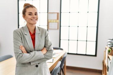 Young woman business worker standing with arms crossed gesture at office
