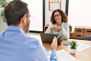 İki orta yaşlı iş adamı ofiste konuşurken gülümsüyor..