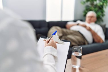 Orta yaşlı, kır saçlı bir adam psikoloji kliniğinde psikoloji seansı yapıyor.