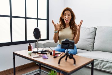 Orta yaşlı İspanyol kadın evde akıllı telefonuyla makyaj dersi kaydediyordu. Deli gibi bağırıyor, agresif bir ifade ve kollar havada bağırıyordu. hüsran kavramı. 