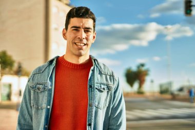 Genç İspanyol adam gülümseyerek şehirde mutlu mesut dikiliyor..