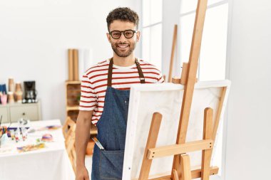 Sanat stüdyosundaki Arap genç adamın yüzünde mutlu ve havalı bir gülümseme vardı. şanslı kişi. 