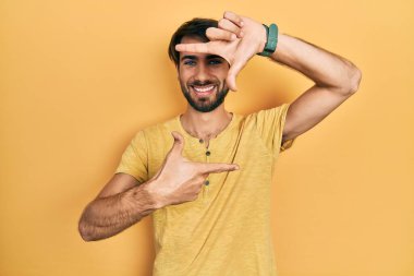 Gündelik kıyafetler giyen, gülümseyen, elleri ve parmakları gülen yüzlü, çerçeveli bir İspanyol. yaratıcılık ve fotoğrafçılık kavramı. 
