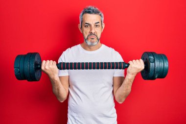 Yakışıklı, orta yaşlı, gri saçlı spor giyimli, halterli, bunalımlı, sıkıntılı, sinirli ve korkmuş bir adam. hüzünlü ifade. 