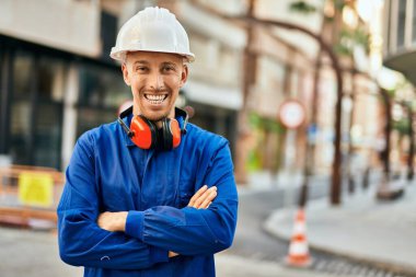 Genç beyaz işçi şehirde üniforma giyerek gülümsüyor..