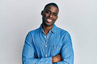 Sıradan kıyafetler giyen, kollarını kavuşturup kameraya gülümseyen Afro-Amerikan genç adam. pozitif kişi. 