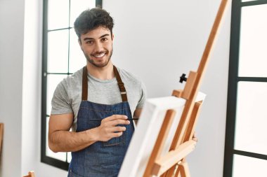 Resim stüdyosunda gülümseyen genç İspanyol ressam..