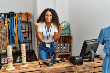 Giyim mağazasında çalışan güzel İspanyol kadın gururla bağırıyor zaferi kutluyor ve başarıyı kollarını kaldırarak kutluyor. 