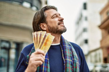 Kasabada Norveçli banknotları tutan orta yaşlı yakışıklı bir adam var.