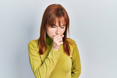 Kızıl saçlı, boğazlı kazak giyen genç bir kadın kendini kötü hissediyor ve soğuk algınlığı veya bronşitin belirtisi olarak öksürüyor. sağlık hizmeti kavramı. 