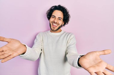 Yakışıklı, beyaz süveter giyen, neşeli gülümseyen, yardım eli uzatan ve kabul gören bir İspanyol.. 