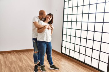 Genç İspanyol çift mutlu bir şekilde gülümsüyor ve boş yeni evlerinde sarılıyorlar..