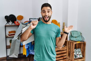 Perakende mağazasında sakallı, alışveriş torbaları tutan genç yakışıklı bir adam. Elinde avuç içi açık, fotokopi alanı gösteren, mutlu bir gülümseme reklamı sunan. 