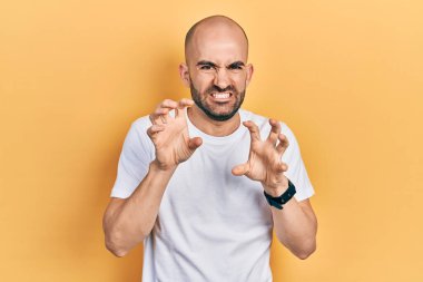 Genç kel adam, günlük beyaz tişört giyip gülümsüyor. Pençe hareketlerini kedi gibi yapıyor. Agresif ve seksi bir ifade. 