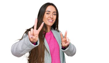 İş kıyafetleri giymiş, gülümseyen genç İspanyol kız kameraya bakıp zafer işareti yapıyor. İki numara.. 
