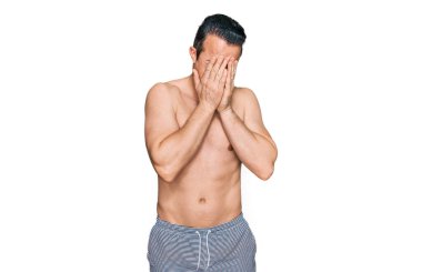 Ağlarken yüzünü ellerle kapatan, mayolu, üzgün yüzlü yakışıklı bir genç. depresyon kavramı. 