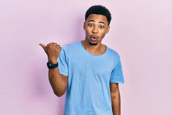 若いアフリカ系アメリカ人男性を着てカジュアルな青Tシャツ驚くべきポインティングで手指で側に オープン口驚き式 — ストック写真