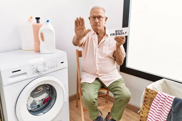 洗濯機を保持するシニア男環境に優しい紙でオープン手を行います停止標識で真剣で自信を持って式 防衛ジェスチャー — ストック写真