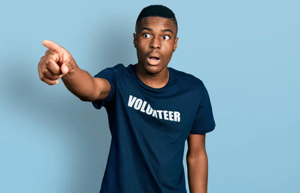 Joven Hombre Afroamericano Vistiendo Camiseta Voluntaria Señalando Con Dedo Sorprendido —  Fotos de Stock