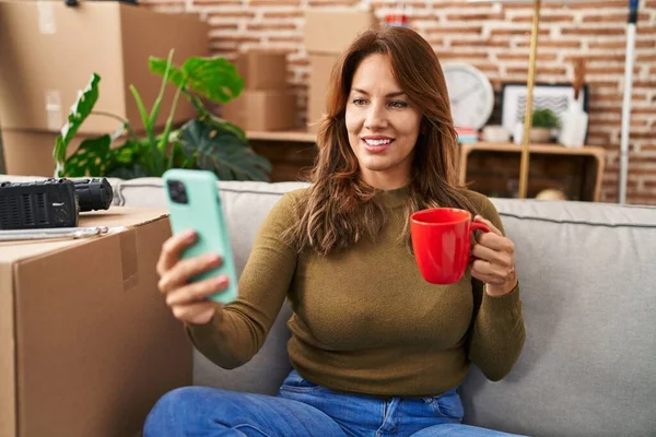 Mujer Latina Joven Bebiendo Café Usando Teléfono Inteligente Sentado Sofá — Foto de Stock