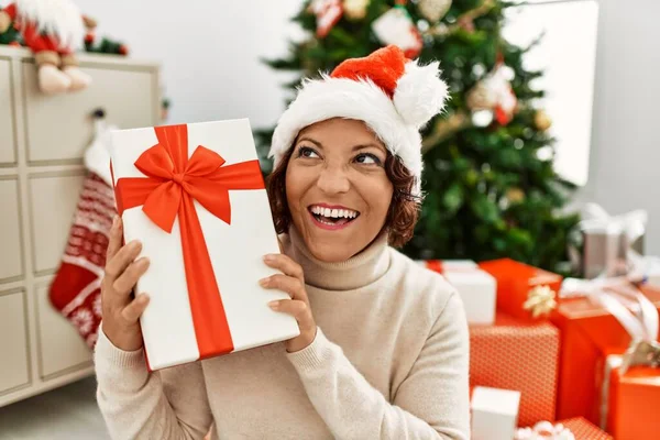 Middle Age Hispanic Woman Holding Gift Sitting Christmas Tree Home — Stock Photo, Image