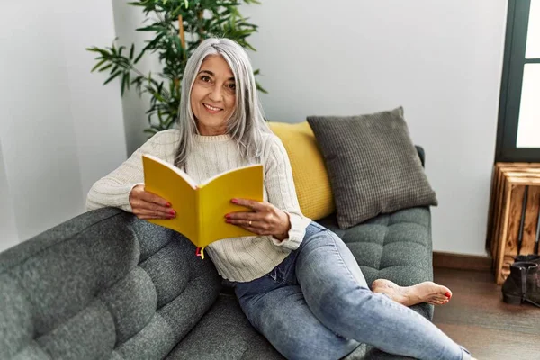 Mujer Pelo Gris Mediana Edad Sonriendo Libro Lectura Segura Casa — Foto de Stock