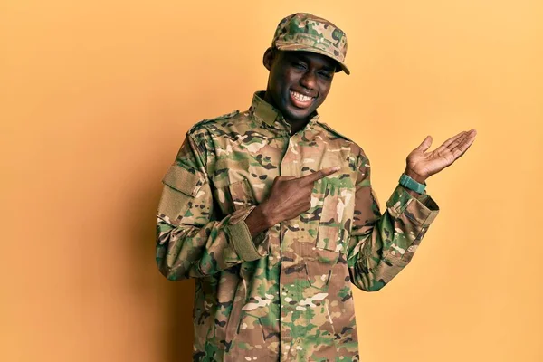 手で提示し 指で指している間 若いアフリカ系アメリカ人の男性は 軍の制服を着てカメラに驚いて笑顔 — ストック写真